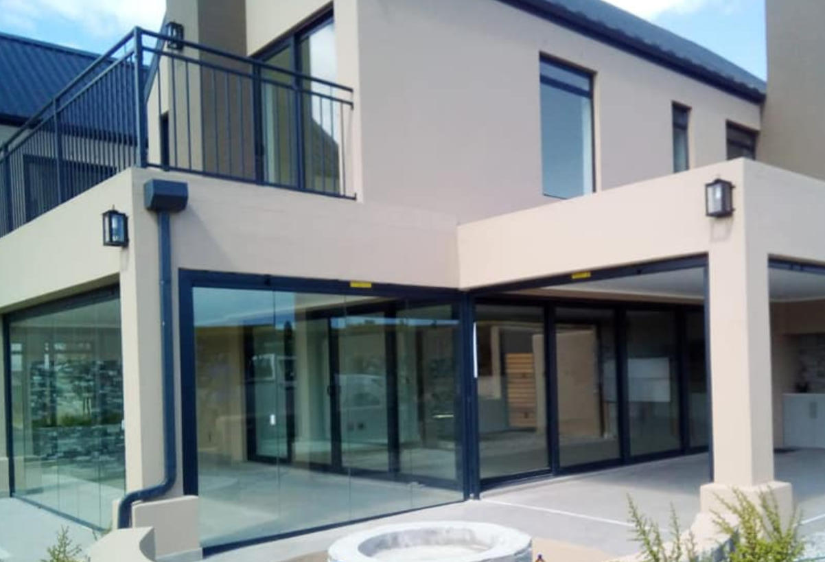 Close up view of professional glass installer working on window frame, clear glass panel being carefully positioned, workshop tools visible